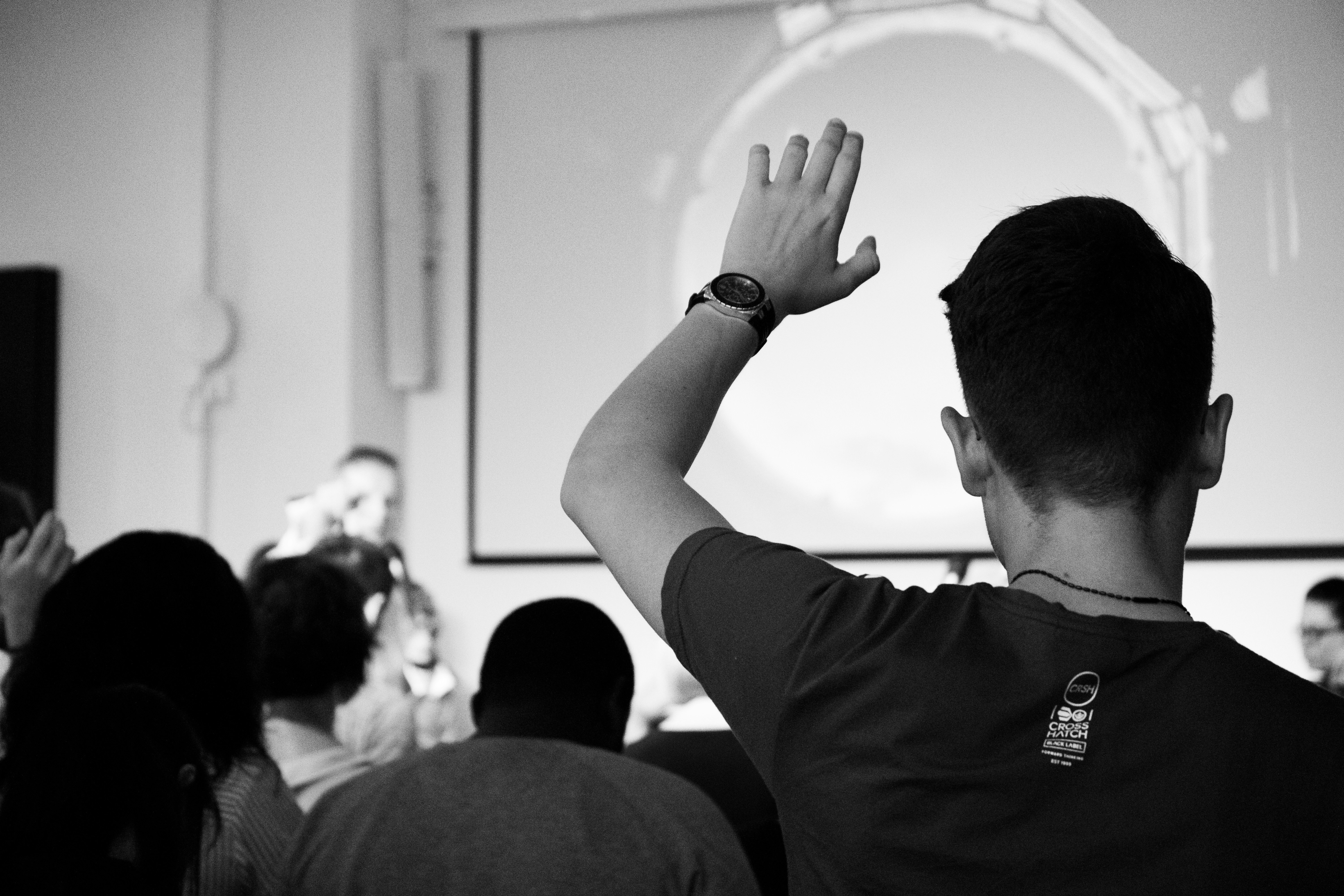 Students in a classroom raising hands during a lesson